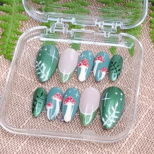 Close up of red mushroom press-on nail kit in acrylic box - red mushrooms with white dots on green background