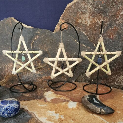 Set of three hemp star ornaments on stands. Crystals in center of stars from left to right: ruby zoisite, amethyst, lapis lazuli.