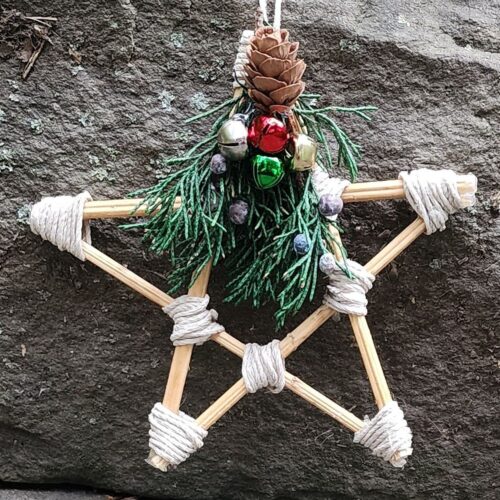 5 inch star made from hemp stalk with points wrapped in hemp twine ad decorated with dried juniper, metal jingle bells and mini pinecone