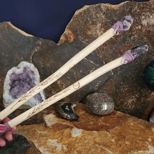 Close up of hand holding a pair of hemp wands tipped with amethyst