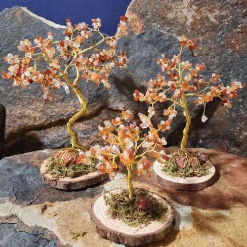 Handcrafted gold wire and carnelian gemstone Tree of Life in Sapling (small), Woodland (medium), and Ancient (large) sizes on natural wood bases with natural moss and stone mushrooms.